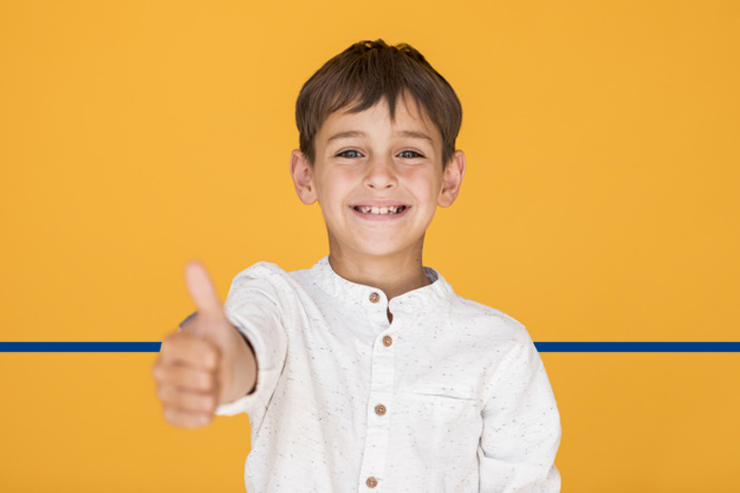 criança sorrindo fazendo sinal de positivo com a mão