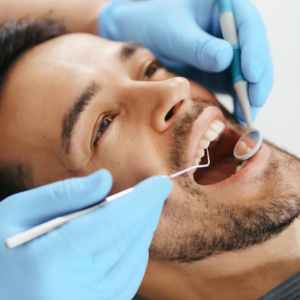 Imagem Jovem sorridente sentado na cadeira do dentista enquanto o médico examina os dentes