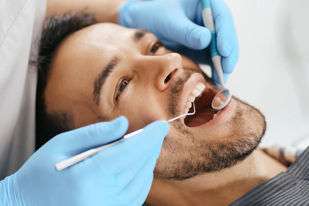 Imagem Jovem sorridente sentado na cadeira do dentista enquanto o médico examina os dentes