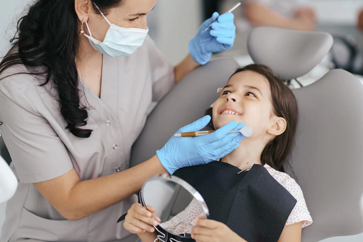 Imagem menina sorrindo enquanto é atendida pela dentista